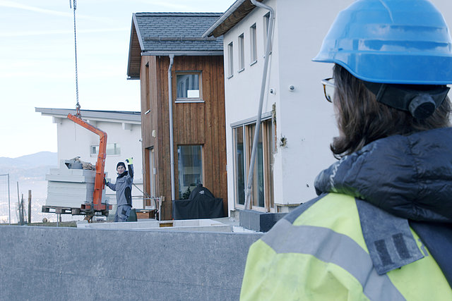 Mann beaufsichtigt Arbeiter, der Kranfahrer Anweisungen gibt