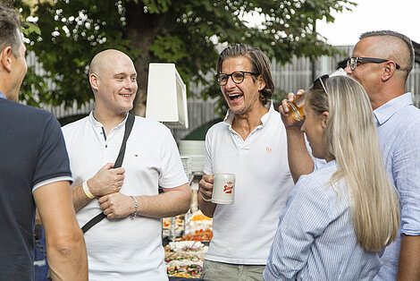 Menschen stehen zusammen, trinken und lachen 