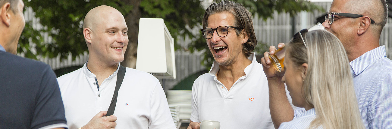 Menschen stehen zusammen, trinken und lachen