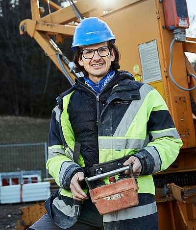 Chef mit Helm und Kransteuerung