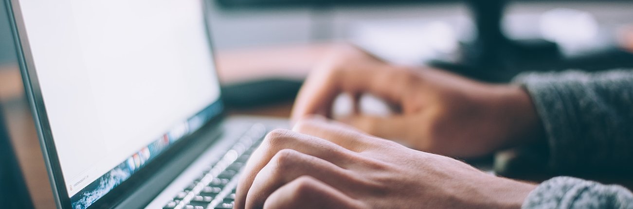 Laptop mit zwei Händen auf Tastatur 