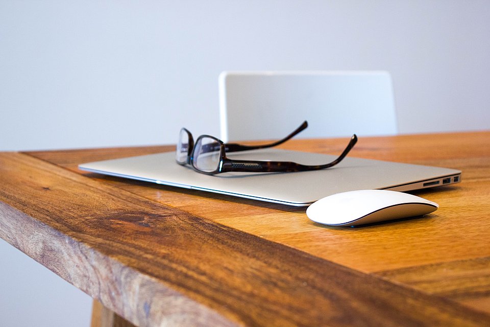 Laptop auf Tisch mit Brille und Maus